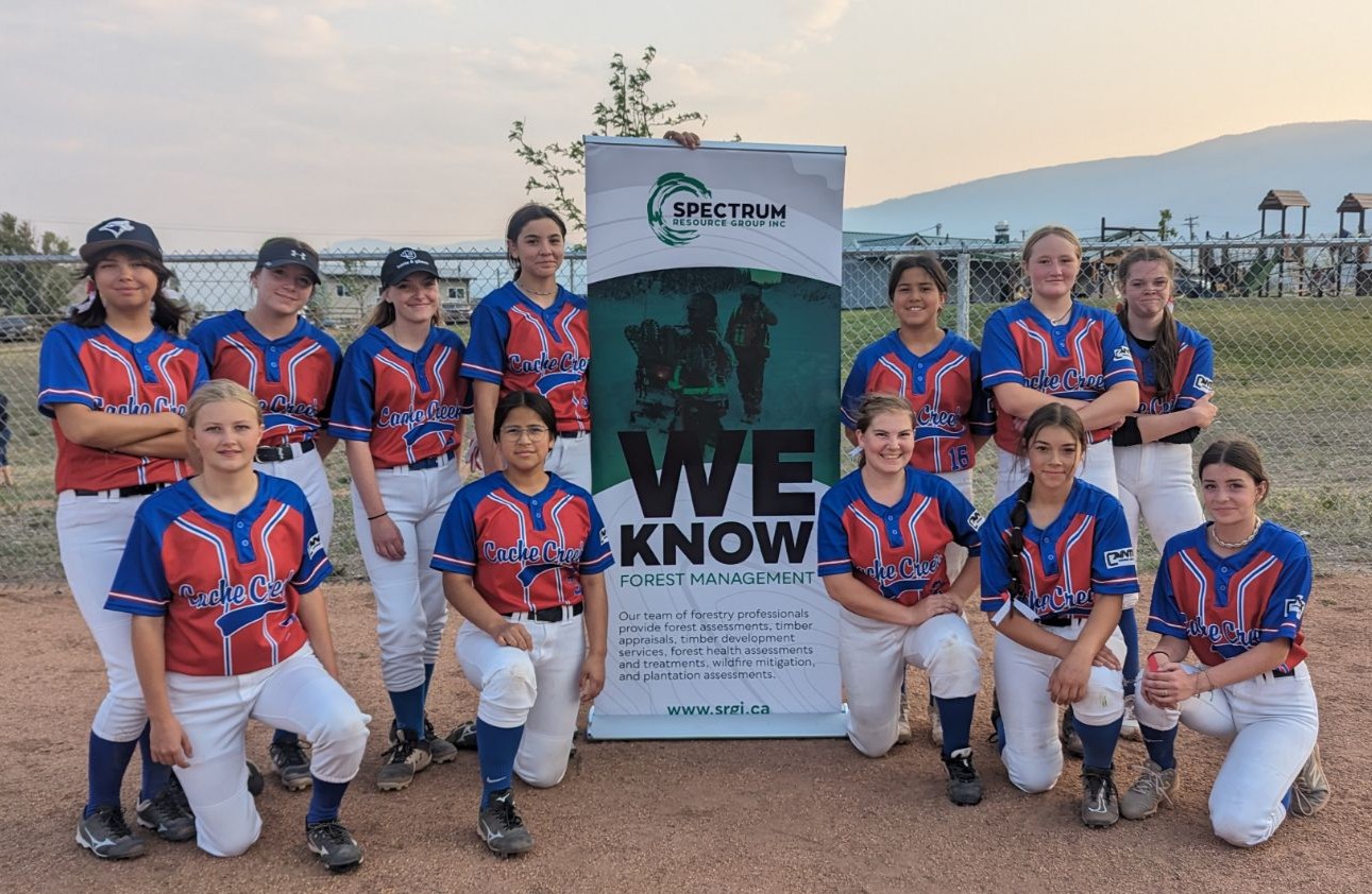 group of girls in softball uniforms posing next to a sign